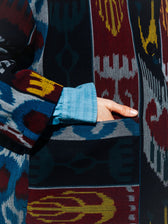 Jana ikat cotton jacket detail — hand in the patch pocket, handwoven ikat in burgundy, black, blue and mustard